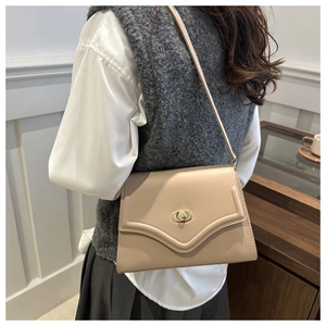 Beige faux leather shoulder bag with gold twist lock shown on a model for scale