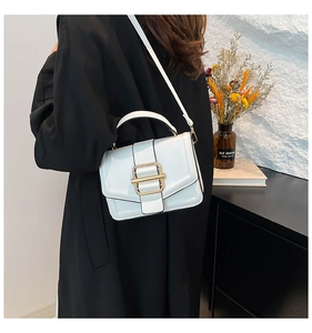 Detail of white glossy small square bag with golden buckle and top handle being carried