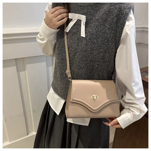 Detail of minimalist beige envelope shoulder bag with gold twist lock and V-flap design