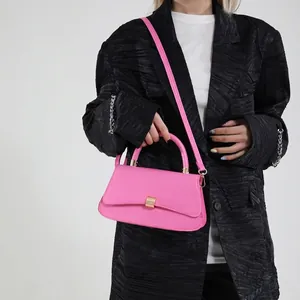Chic pink hourglass shoulder bag with gold hardware worn by a model in a blazer