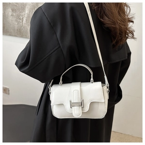 Close-up of a white minimalist small square handbag with silver metal buckle on a black coat