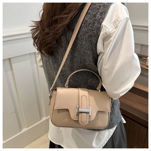 Detailed side view of beige small crossbody bag with silver buckle worn by a model