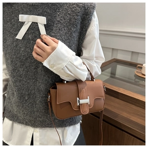 Detail shot of caramel PU leather flap bag with silver clasp and premium stitching