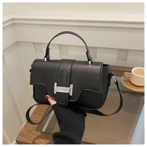 Detail of chic black matte leather handbag with silver lock and adjustable shoulder strap