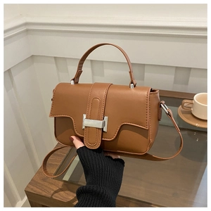 Detailed view of caramel leather square bag with silver H-buckle and top handle