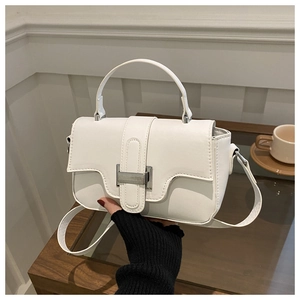 Detail view of white leather square handbag featuring a silver metal buckle and long strap