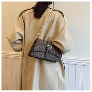 Brown monogram crossbody bag with silver chain strap shown on a trench coat outfit