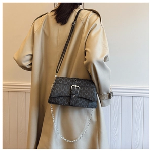 Detail of retro crossbody bag with monogram pattern and silver buckle on model