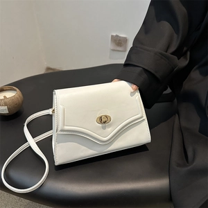 White structured leather underarm bag with gold oval twist lock on black background