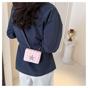 Pink mini quilted chain bag with diamond star charm worn by a model in a natural setting