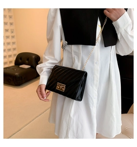 Detailansicht der schwarzen Stepptasche mit Goldkette und Chevron-Muster