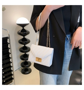 Tragefoto einer weißen Stepptasche mit goldener Kette und quadratischem Metallverschluss