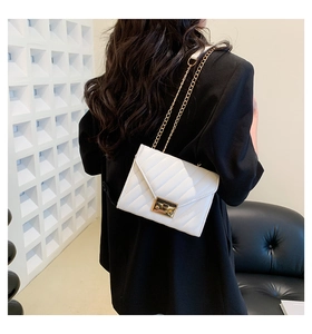 Detail der weißen Stepphandtasche mit goldener Kette und quadratischem Drehverschluss