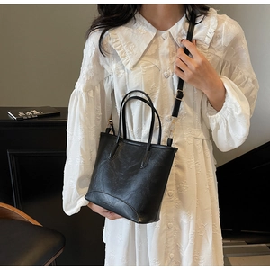 Model wearing a black bucket bag with a white lace shirt for a casual cross-body look