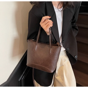 Detail of dark brown bucket bag with lychee texture and versatile shoulder straps