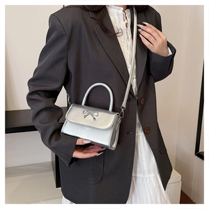Detail of silver metallic mini crossbody bag with metal bow clasp on a model