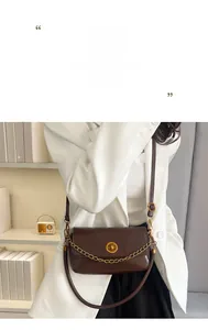 Détail d'un sac à bandoulière en cuir marron avec un fermoir pivotant rond en métal doré
