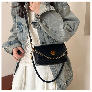 Détail d'un sac en cuir noir mat vintage avec fermoir doré et bandoulière en chaîne