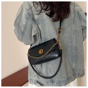 Détail d'un sac à bandoulière noir avec chaîne dorée et sangle en cuir sur modèle