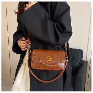 Sac bandoulière vintage en cuir marron avec fermoir doré porté par un mannequin