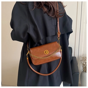 Détail du sac à rabat en similicuir marron avec chaîne dorée et fermoir rotatif en métal