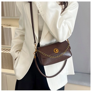 Détail du sac vintage marron foncé avec chaîne dorée et fermeture par fermoir rotatif