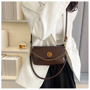 Détail d'un sac bandoulière marron foncé avec fermoir anneau doré et chaîne décorative