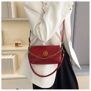 Photo de style d'un sac bandoulière rouge vintage avec chaîne bronze et fermoir rotatif