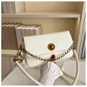 Détail d'un sac porté épaule en cuir blanc crème avec fermoir doré et chaîne décorative