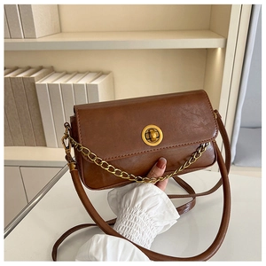 Détail d'un sac à main vintage marron avec fermoir tournant doré et chaîne en métal