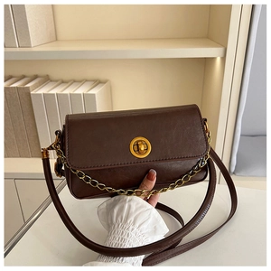Détail du sac bandoulière en cuir marron foncé avec fermoir rotatif doré et chaîne