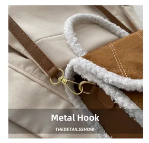 Close-up of golden metal spring hook and sherpa trim on brown suede crossbody bag