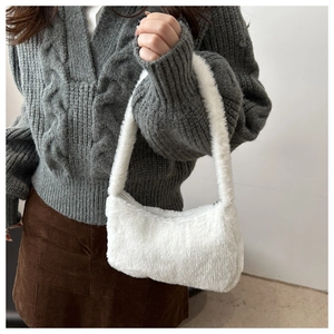 Gros plan sur le sac sous l'aisselle en peluche blanche avec texture douce en fausse fourrure