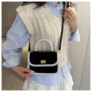 Detail of quilted black handbag with white faux fur trim and gold metal twist lock