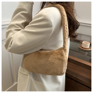 Close-up of plush faux fur underarm bag in light camel worn by a model