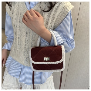 Détail du sac bandoulière bordeaux en daim avec bordure en peluche blanche et fermoir doré