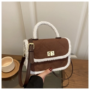 Détail d'un sac bandoulière en daim marron avec bordure en peluche et fermoir en métal doré