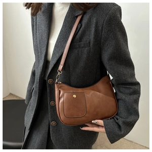 Détail d'un sac bandoulière vintage en cuir marron avec bouton doré et longue lanière