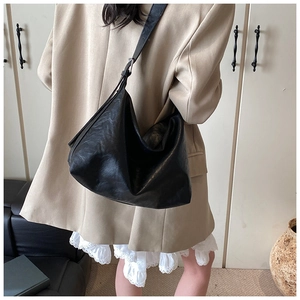 Detail of soft black faux leather texture on large hobo bag with wide shoulder strap