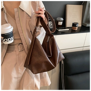 Détail d'un sac hobo en similicuir marron foncé montrant sa texture et sa forme triangle