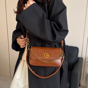 Sac bandoulière marron vintage avec chaîne dorée et fermoir porté par un mannequin
