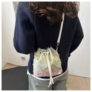 Détail du sac seau à franges avec motifs étoiles et dégradé rose en tissu denim