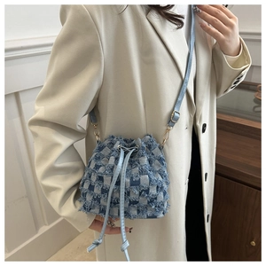 Detail of blue and white checkered denim bucket bag with frayed edges and drawstring