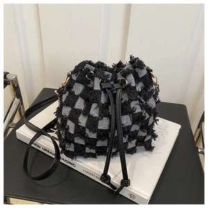 Detail of checkered bucket bag with frayed edges on a minimalist white background