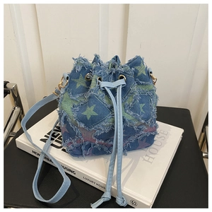 Detail of denim bucket bag with frayed edges and green purple star patterns