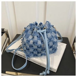 Macro detail of checkered denim bucket bag with frayed edges and drawstring closure