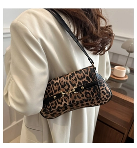 Detail of leopard print underarm bag with gold horsebit hardware worn on cream blazer