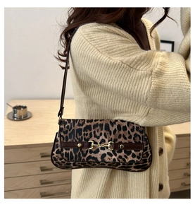 Close-up of leopard print baguette bag with golden horsebit buckle on a model