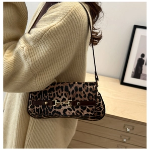 Detail of trendy leopard print baguette bag with golden horsebit buckle on shoulder strap