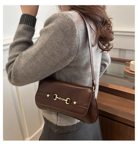 Detail of dark brown leather baguette bag with signature gold horsebit hardware